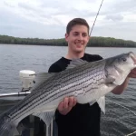 front view of middle aged boy holding large striper caught from fishing trip in nashville given from a gift certificate
